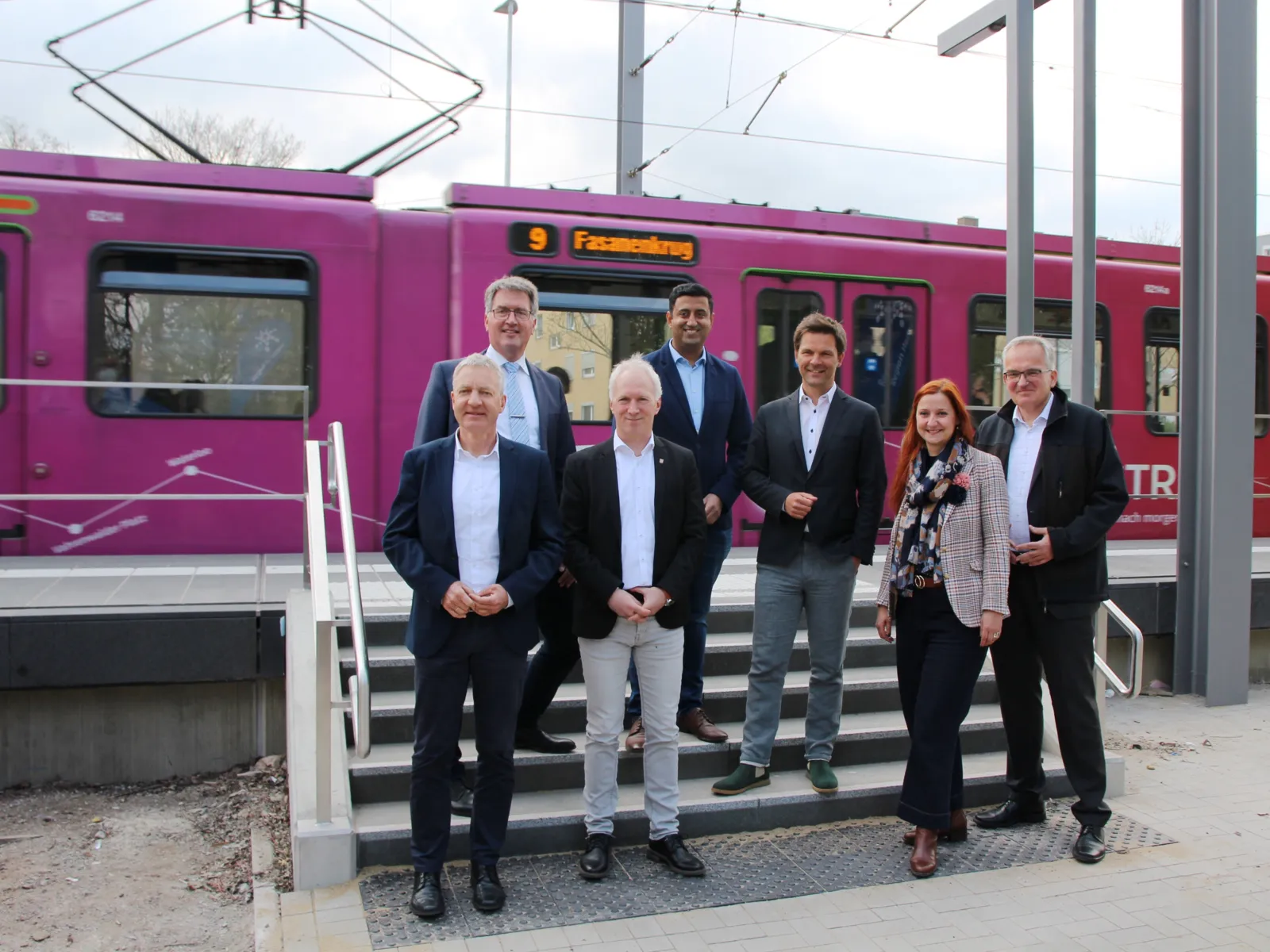 Gruppenbild an einem neuen Hochbahnsteig. Auf dem Gleis ist eine Stadtbahn.